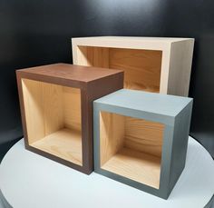 three wooden cubes sitting on top of a white table with black wall behind them