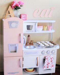 a play kitchen with pink and white appliances