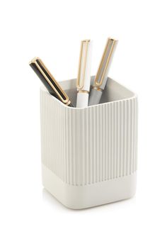 a white container with three pens and two pencils in it on a white surface