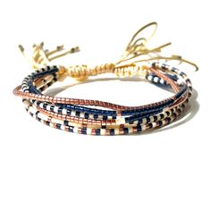 three bracelets with different colored beads and gold clasps on white background, close up