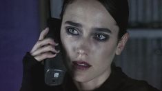 a woman holding a cell phone to her ear and looking at the camera with evil makeup