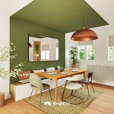 a dining room with green walls and wooden flooring is pictured in this image, there are several chairs around the table