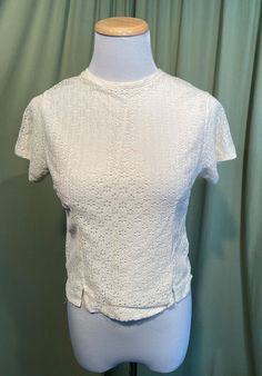 "This is a sweet vintage, lace blouse from the 1950s or 60s. Label is missing, no size tag, the bust measures 32\", but would look best on a slightly smaller bust. Please see measurements below. Made of a rayon or nylon eyelet layer over a silky solid layer in an off white or cream color. Button back , with plastic buttons. The neckline is high & rounded. Hem line is a straight hemline, with small vents over each hip. The blouse is in very good condition! No damage , but it does have a tiny Fitted Vintage White Top With Lace Trim, Fitted Retro Cream Top, Vintage Fitted Lace Top For Spring, Cream Fitted Top With Lace Collar, Fitted Cream Top With Lace Collar, Fitted Cream Lace Top With Short Sleeves, Vintage Lace Tops For Spring, Fitted Lace Vintage Tops, Vintage Cream Tops With Lace Collar