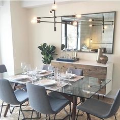 a dining room table set for six with blue chairs and white plates on the wooden floor