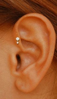 a woman's ear is shown with two small diamond studs on the side