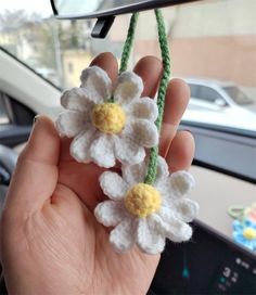 someone is holding up some crocheted flowers in their hand while they are on the dashboard