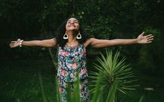 a woman standing in the grass with her arms outstretched