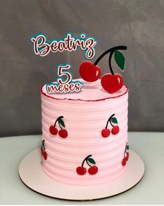 a pink birthday cake with cherries on top