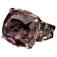 This large and flawless deep purple natural amethyst has been square-cut and placed in a uniquely and intricately hand-carved rhodium plated sterling silver prong setting and band both tastefully ornamented with luxe gold leaf. One round pink and one rare yellow sapphire accent the ring on each side. We resize within 10 business days for a $25 fee. If you select the resize option, please add a note with your order or email us with the size to which you would like your ring adjusted. Size: 7 Dimensions: 20mmW x 30mmD x 18mmH Weight: 12.83 g Square Cut, Yellow Sapphire, Amethyst Ring, Deep Purple, Gold Leaf, Prong Setting, Rhodium Plated, Sapphire Ring, Fashion Rings