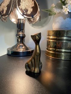 a cat figurine sitting on top of a table next to a lamp