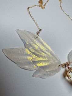 a necklace with a flower shaped glass piece hanging from it's side on a gold plated chain