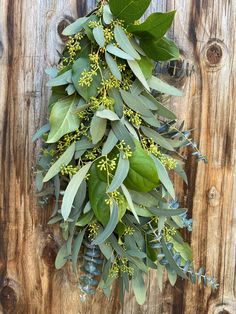 a bunch of green leaves hanging on a wooden wall with some yellow flowers in the middle