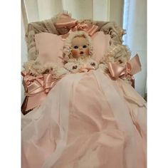 a baby doll is laying in a pink bed with ruffled trims on it's head