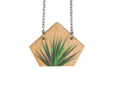 a wooden necklace with a green plant hanging from it's center and two silver chains