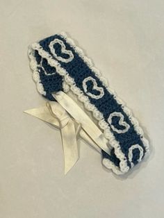 two crocheted headbands with white hearts on blue and white ribbon tied around them