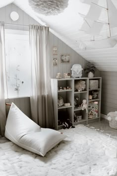 a white bed sitting under a window next to a book shelf filled with stuffed animals