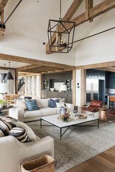 a living room filled with lots of furniture and wooden beams on the ceiling over a fire place