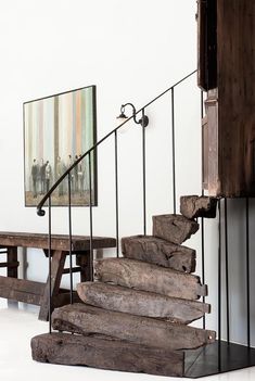 a staircase made out of wood and metal with a painting on the wall behind it