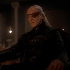 a man with white hair and sunglasses sitting in a chair