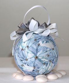 an ornament made out of fabric and ribbon on top of some white rocks