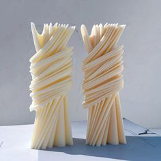 two sculptures made out of white paper on a table