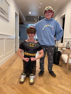 a man standing next to a boy in a batman costume