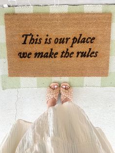 a person standing in front of a door mat that says, this is our place we make the rules