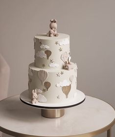 a three tiered cake decorated with animals and hot air balloons is on a table