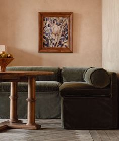 a living room with a couch, table and painting hanging on the wall above it