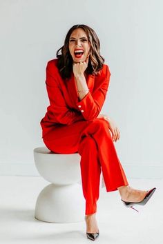 a woman sitting on top of a white toilet wearing red pants and high heels with her mouth open