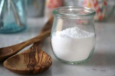 a glass jar filled with white powder next to wooden spoons