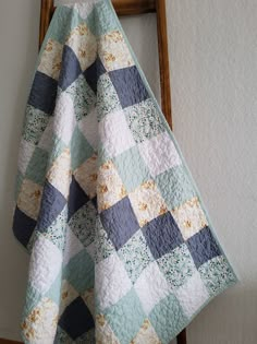 a blue and white checkered quilt hanging from a wooden ladder next to a wall