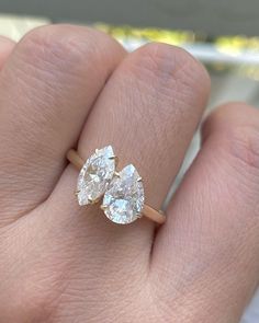 a woman's hand with two pear shaped diamonds on top of her finger,