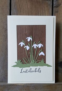 a card with white flowers on it sitting next to a wooden fence and the words lintbubbles