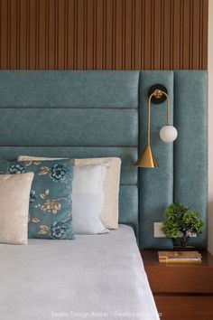 a bed with blue headboard and pillows on top of it next to a night stand