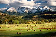 there are many bales in the field with mountains in the backgroung