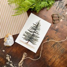 a card with a pine tree drawn on it next to some scissors and other crafting supplies