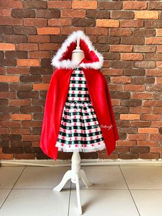 a dress and coat are on display in front of a brick wall with a white mannequin