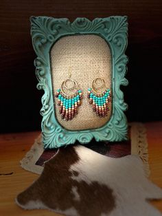 Add a touch of boho-chic to your look with these handmade Western-style chandelier earrings. Featuring a gold-tone circular hoop design adorned with turquoise, pearly gold, and brown dangling beads, these earrings bring a Native American-inspired flair to any outfit. The intricate inner loops and cascading strands create a mesmerizing effect, perfect for both casual days and special occasions. Crafted with care, these bohemian dangle earrings are a versatile addition to your jewelry collection, effortlessly blending Western charm with contemporary style. Bohemian Gold Beaded Small Hoop Earrings, Gold Bohemian Beaded Small Hoop Earrings, Gold Bohemian Small Hoop Beaded Earrings, Bohemian Small Hoop Earrings With Gold Beads, Bohemian Turquoise Earrings With Gold Beads, Bohemian Gold Bead Hoop Earrings, Bohemian Wire Wrapped Round Chandelier Earrings, Bohemian Chandelier Earrings With Gold Beads, Bohemian Gold Beaded Dangle Chandelier Earrings