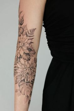 a woman's arm with flowers and leaves tattooed on the left side of her arm