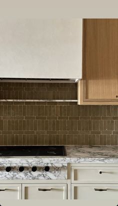 a stove top oven sitting inside of a kitchen next to white cupboards and drawers