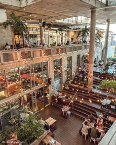 an indoor restaurant with tables and stairs leading up to the second floor, filled with people