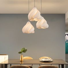 a dining room table with chairs and lights hanging from the ceiling