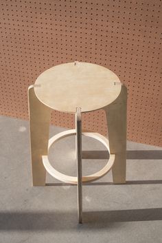 a small table sitting on top of a cement floor next to a wall with holes in it