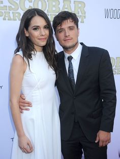 a man and woman standing next to each other on a red carpet