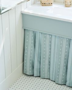 a blue and white bathroom with striped curtains