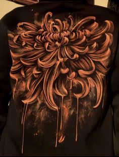 the back of a person wearing a black hoodie with an orange flower on it