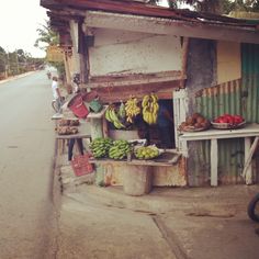 there is a fruit stand on the side of the road with bananas and other fruits