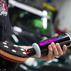 a person is holding a black and pink device in their left hand, with a sponge on it