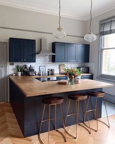 a kitchen island with three stools next to it and a window in the background